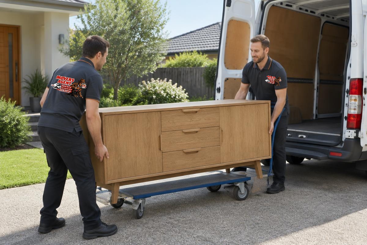 Two delivery workers moving a wooden sideboard from a van on a furniture trolley